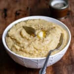 Close up of a dish of pease pudding with a spoon in it.