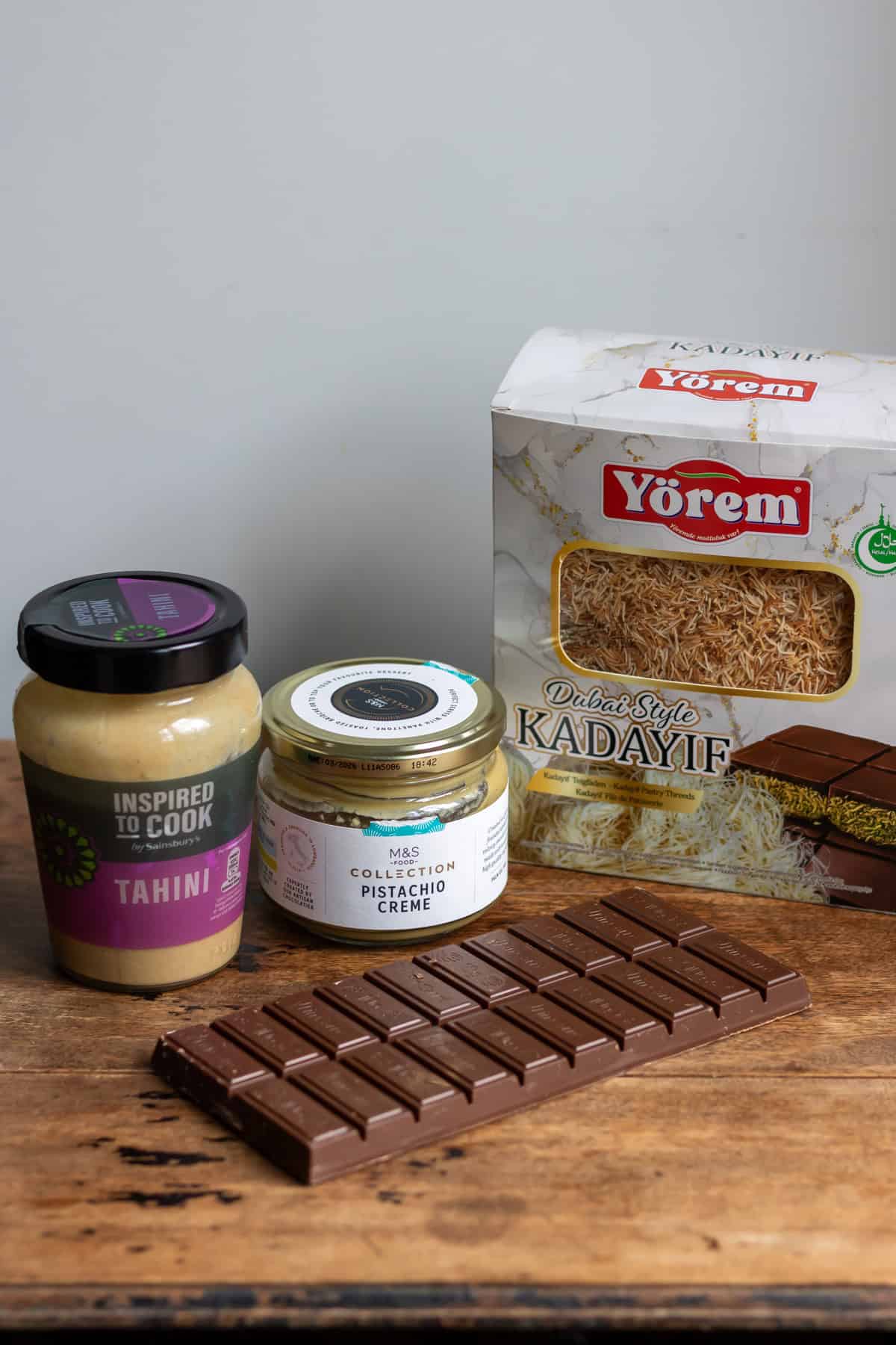 Kadayif, pistachio creme, tahini and chocolate on a table.