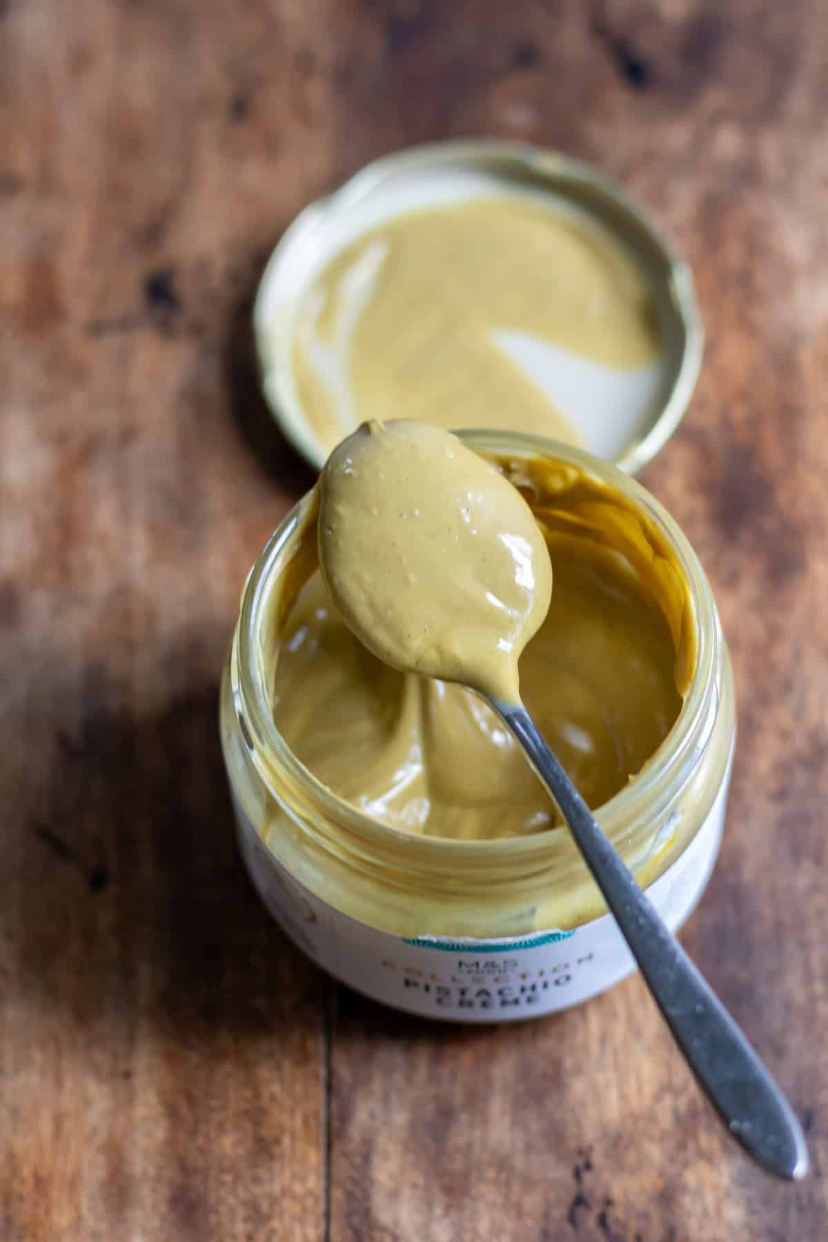 A spoonful over a jar of pistachio creme.