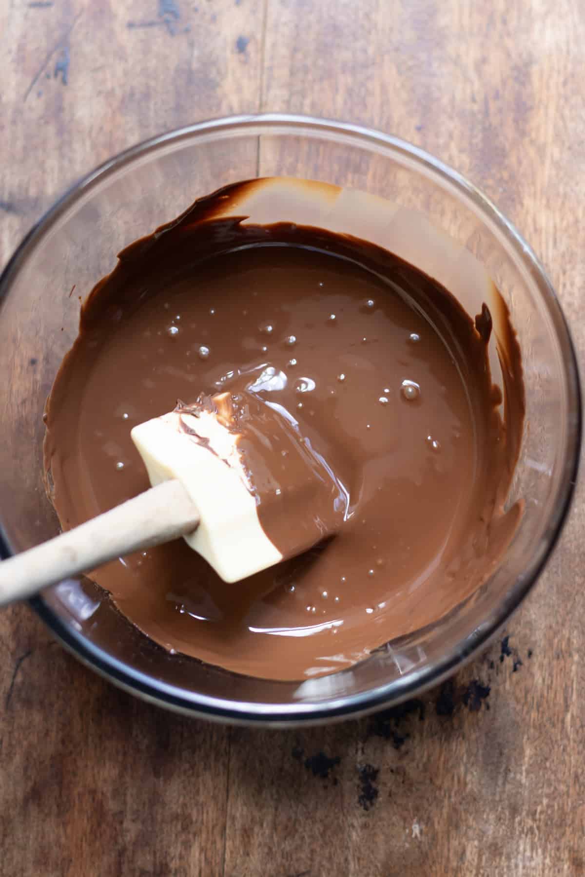 Stirring melted chocolate in a bowl.