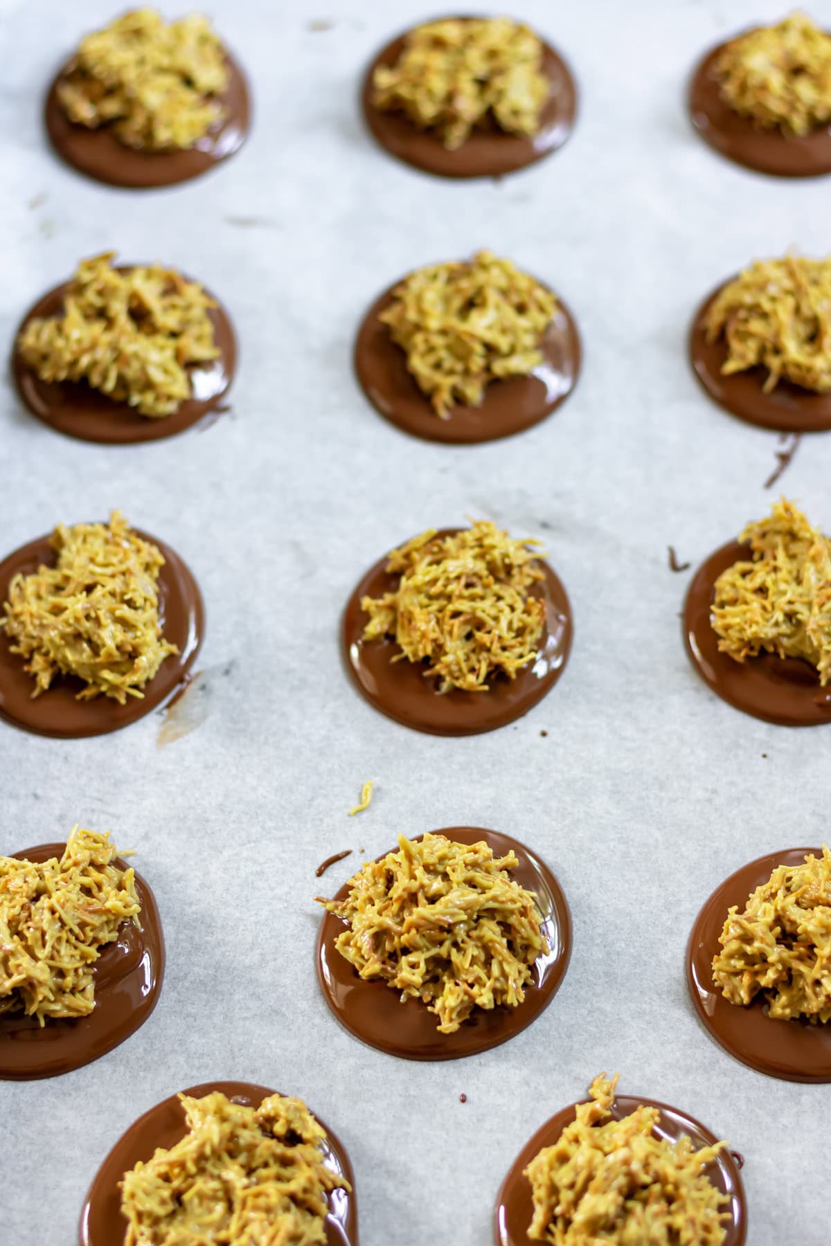Adding small scoops of the pistachio kadayif mixture to each melted chocolate disc.