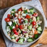 A table with a serving dish of greek bean salad.