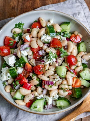 A table with a serving dish of greek bean salad.