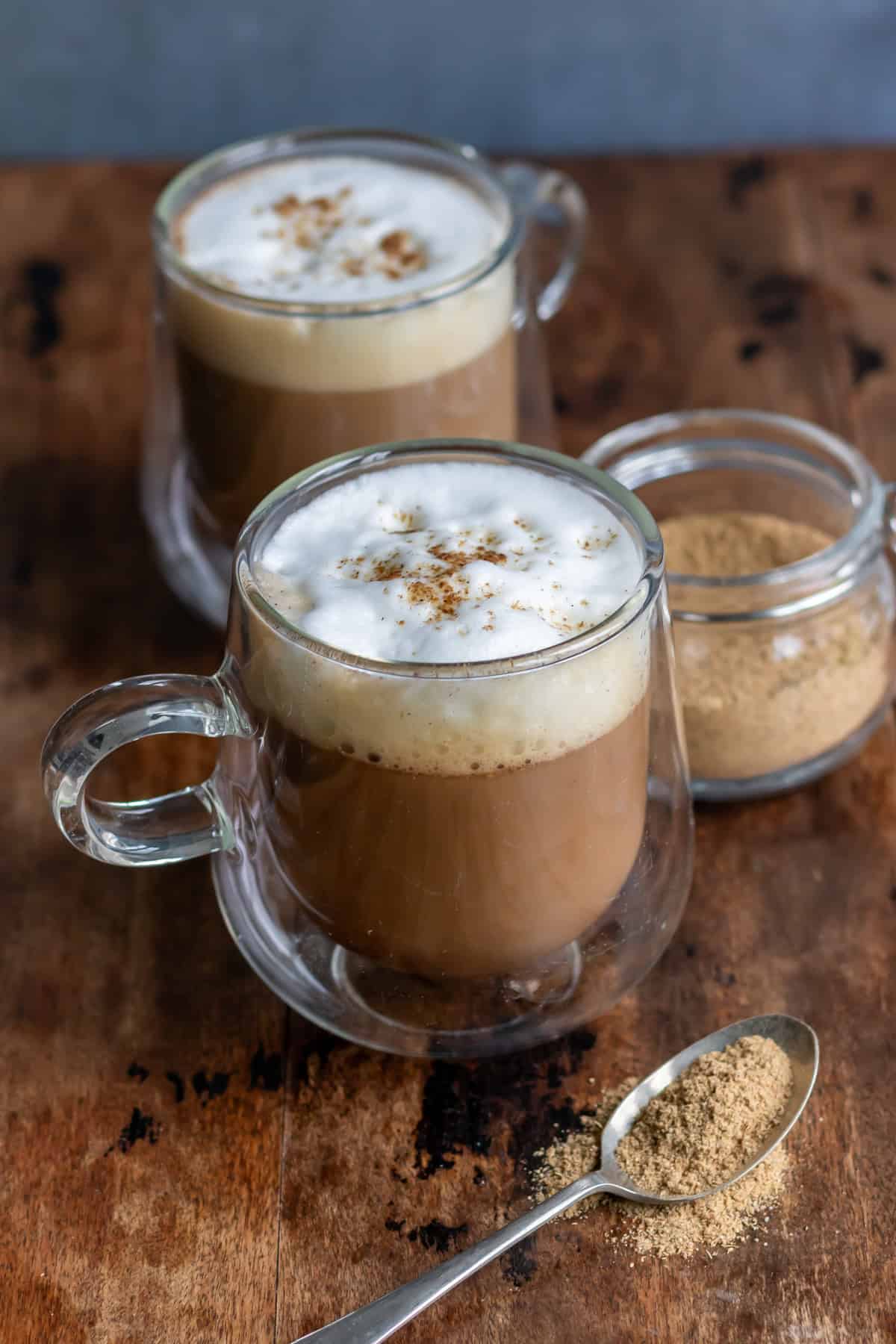 Two glass mugs of sweet hawaij coffee on a wooden table.