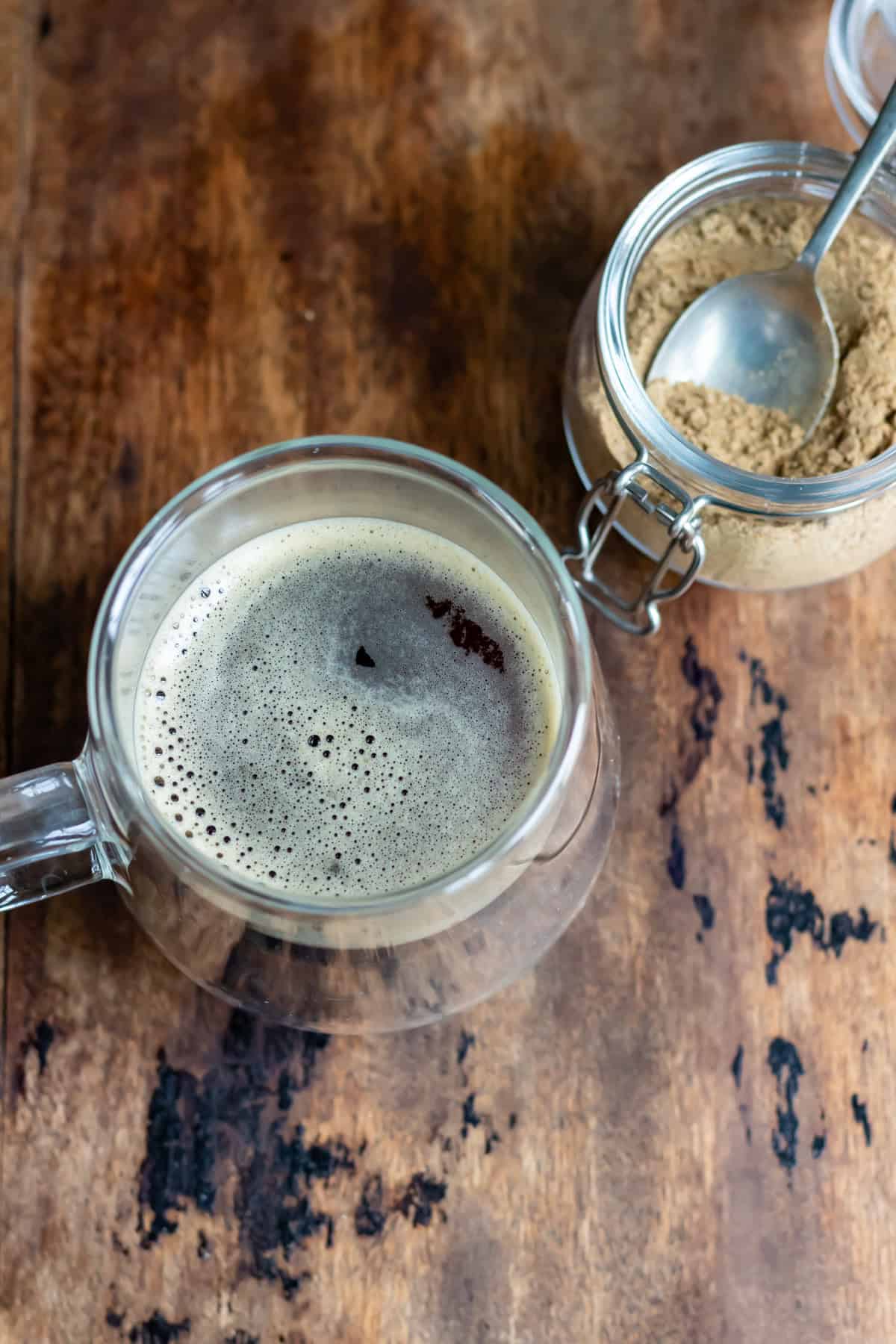 A mug of coffee next to a jar of sweet hawaij.