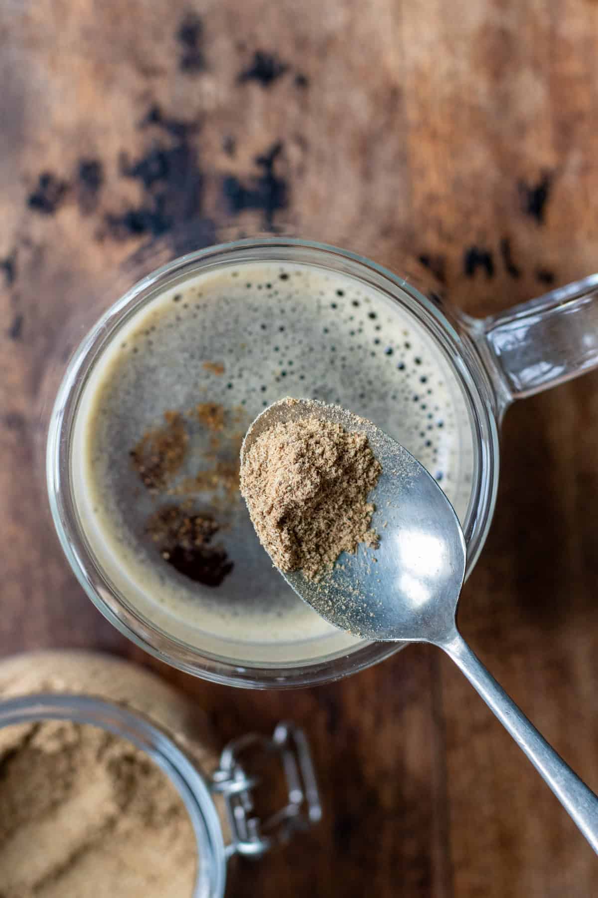 Adding a spoonful of sweet hawaij to the coffee.