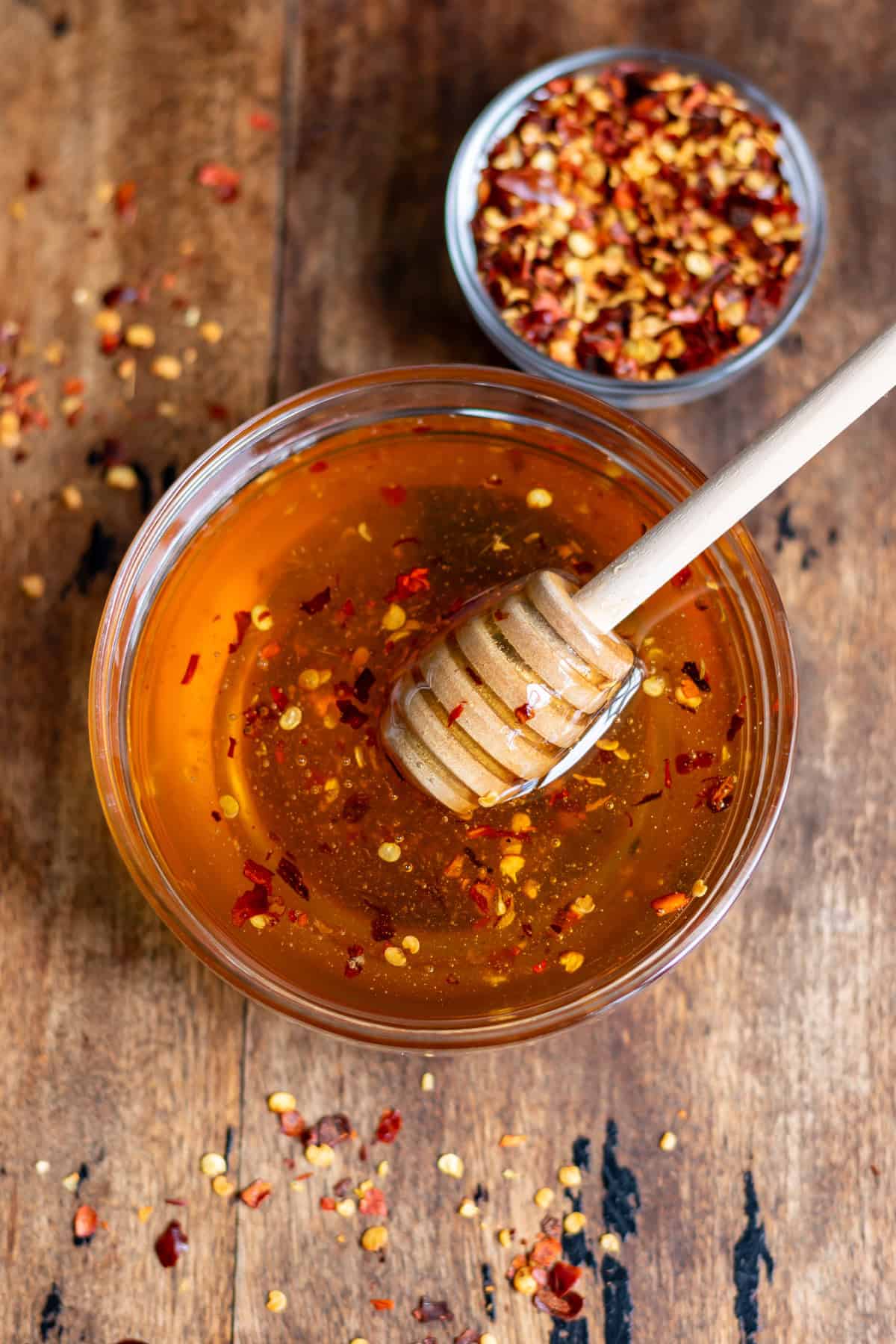 Hot honey with chili flakes in a bowl on a wooden table.
