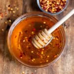 Hot honey with chili flakes in a bowl on a wooden table.