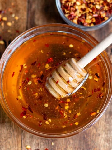 Hot honey with chili flakes in a bowl on a wooden table.