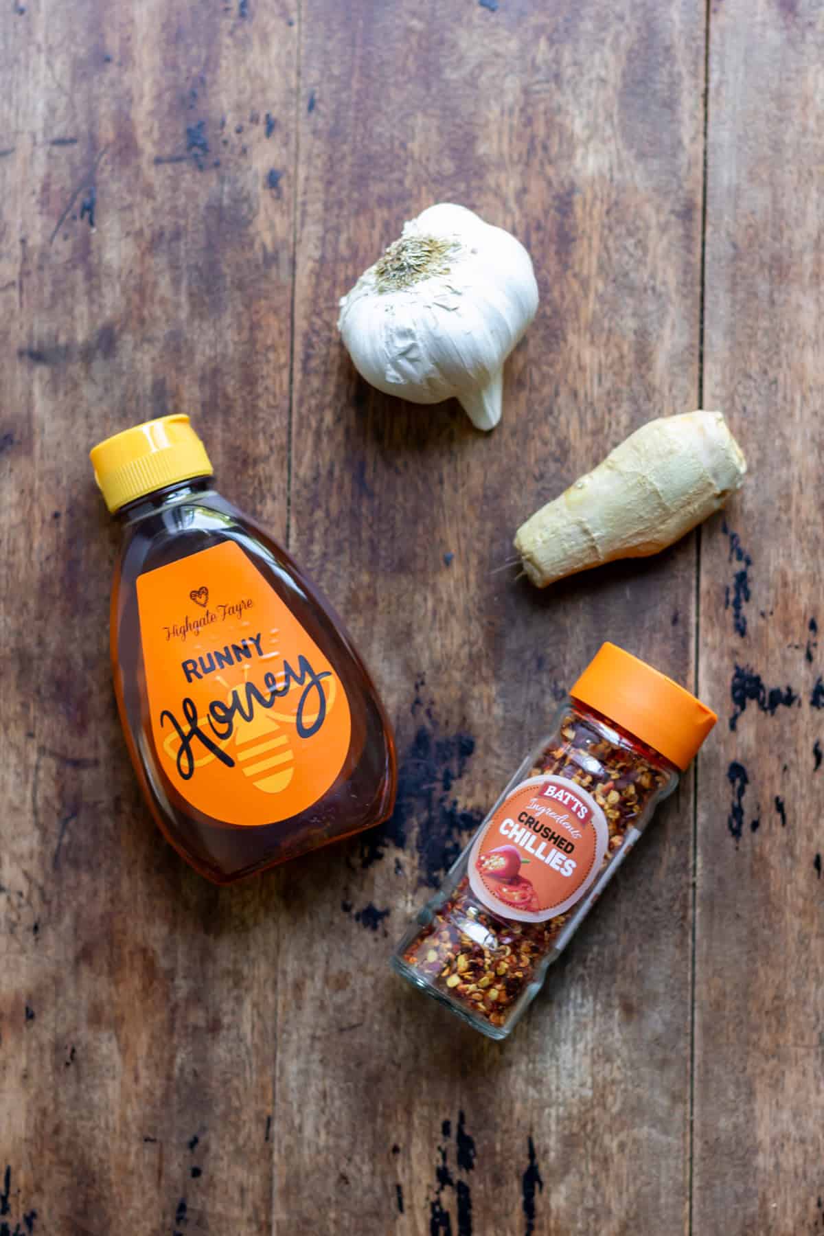 Honey, garlic, ginger and chili flakes on a table.
