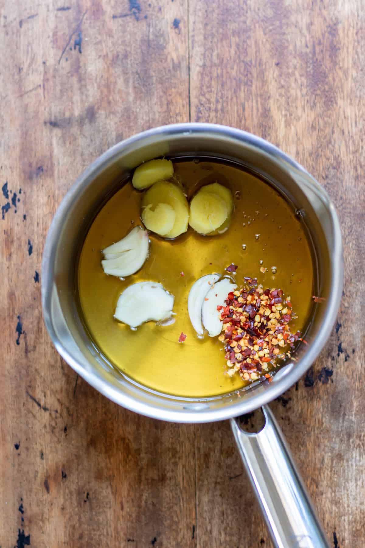 Honey, chili flakes, ginger and garlic in a pot.