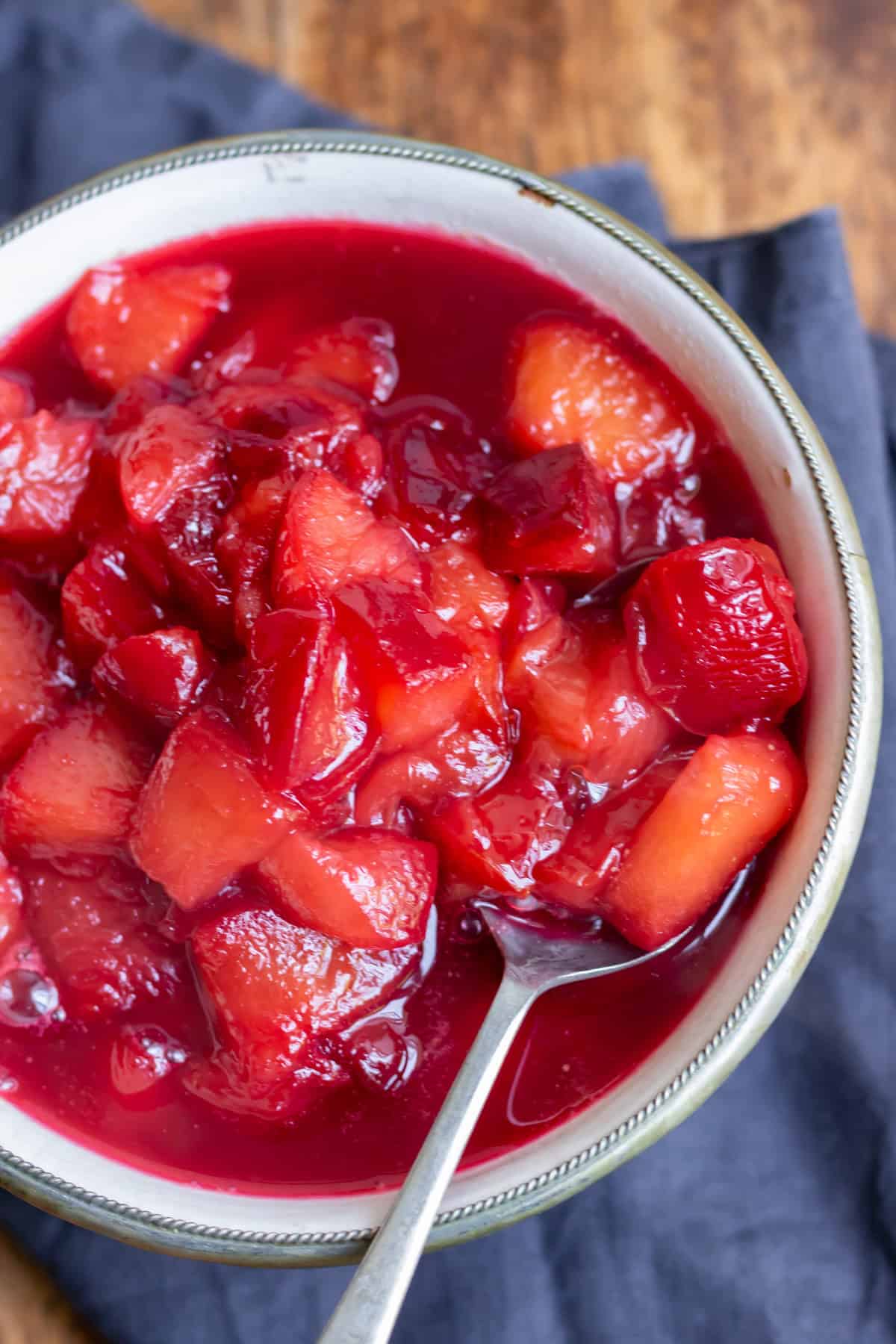 Close up of a spoon in a dish of plum compote.