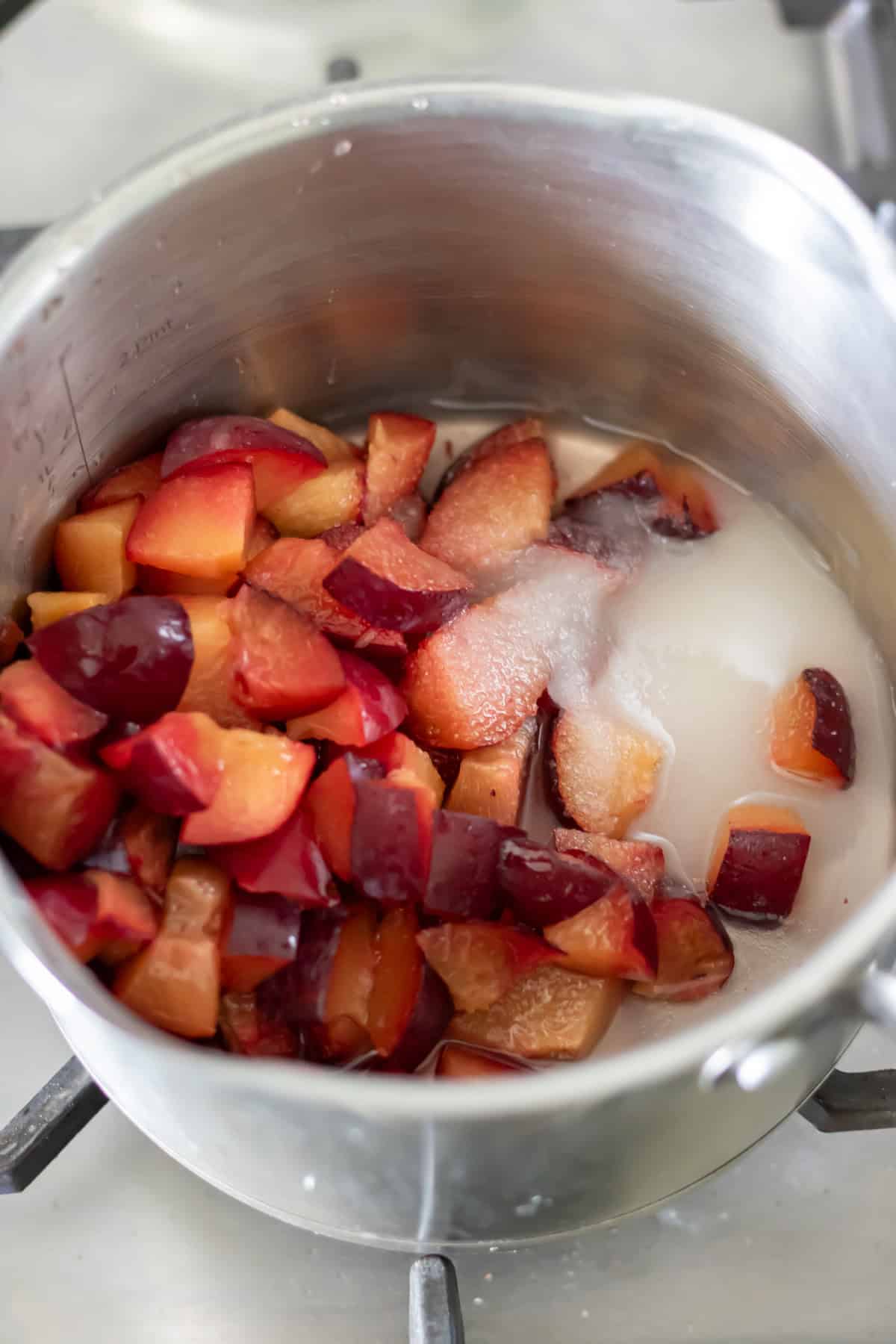 A pot with water, chopped plums and sugar.