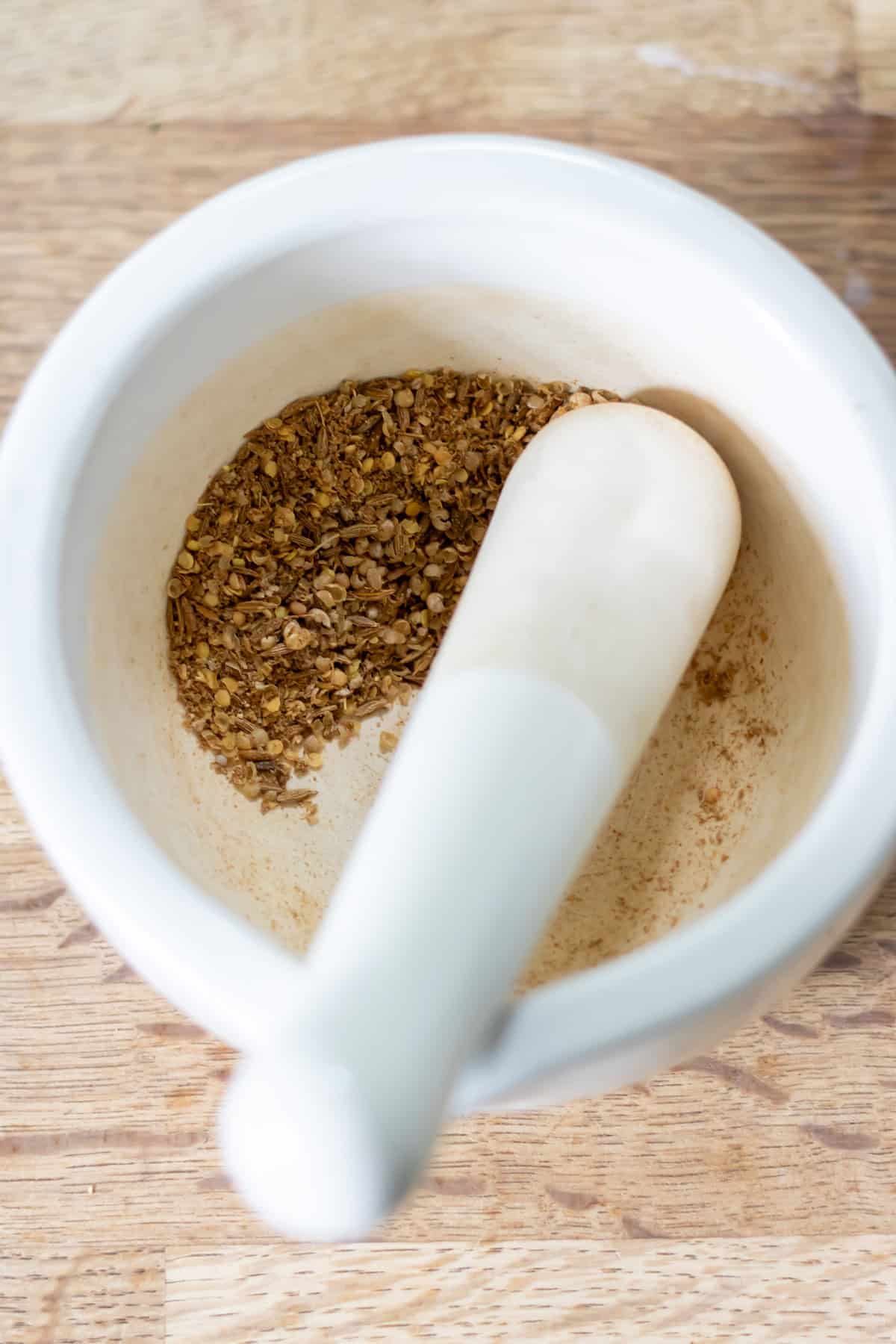 Grinding whole spices in a pestle and mortar.