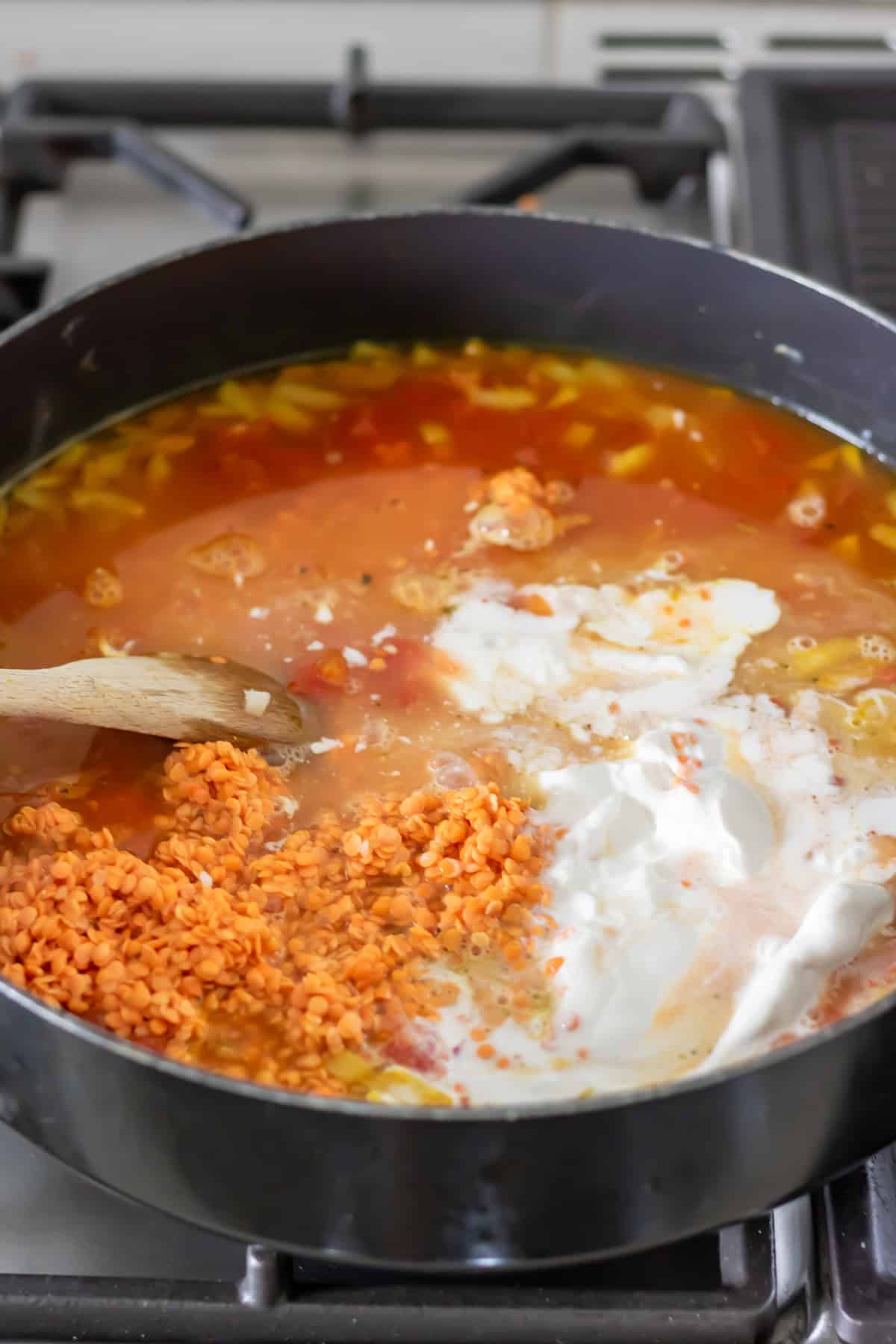Red lentils, stock, tomatoes, and coconut milk added to the pan.