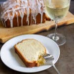 A slice of white wine cake with a glass of white wine.