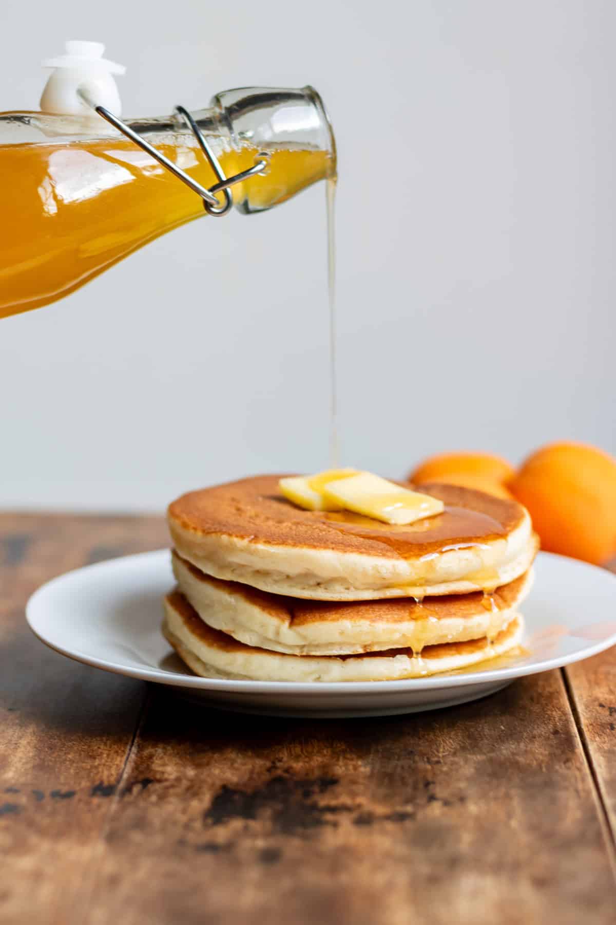 Pouring apricot syrup on a stack of pancakes.