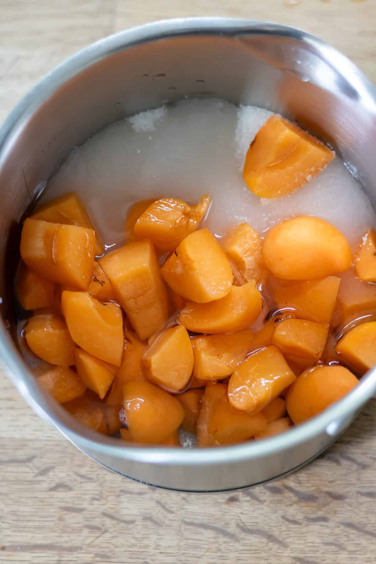 A pot with water, sugar and chopped apricots.