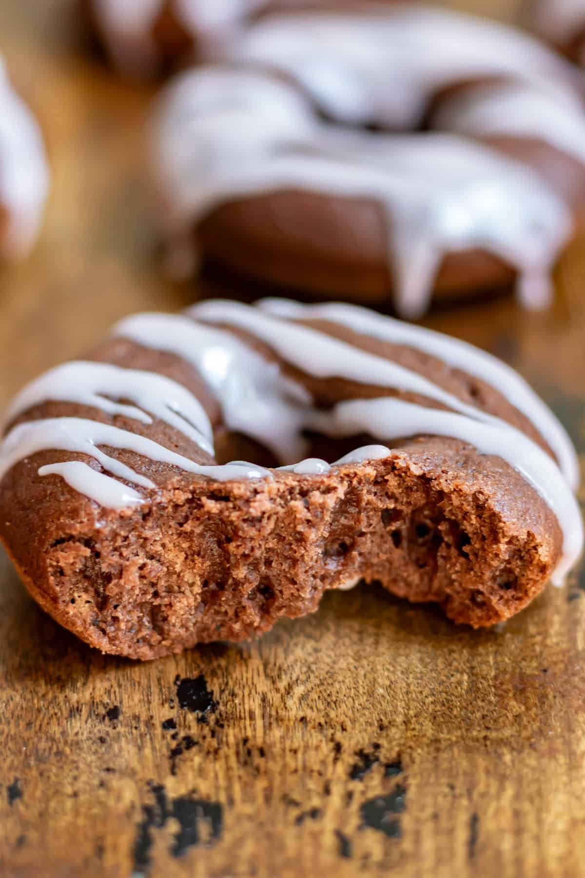 A beet chocolate donut with a bite out.