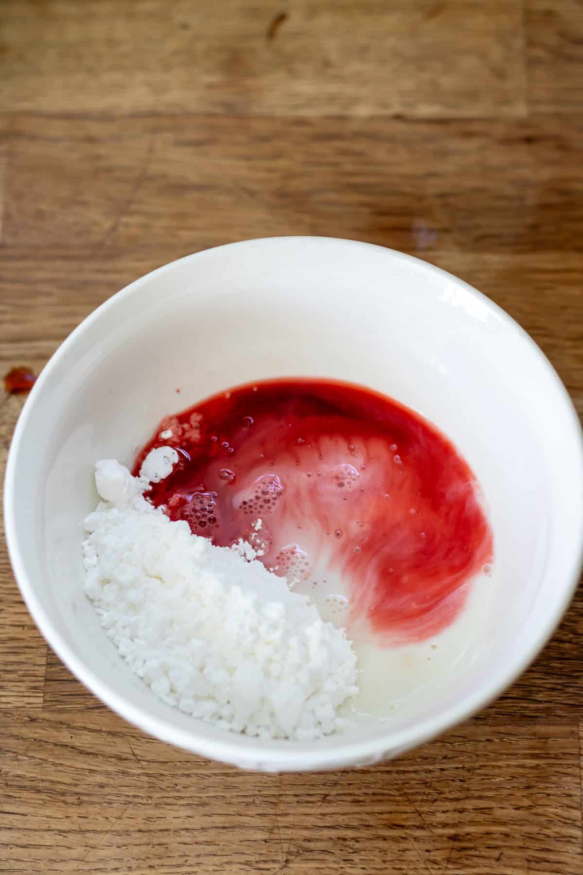 Powdered sugar, beet juice and milk in a bowl.