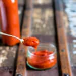 Spoon coming out of a dish of homemade tomato ketchup.