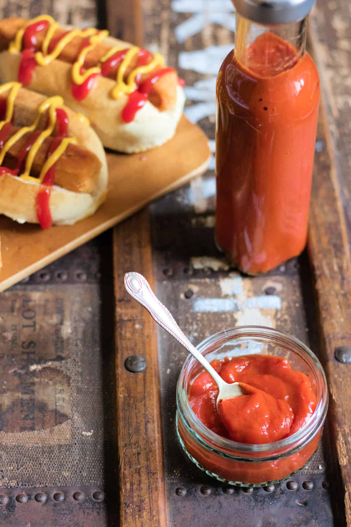 Looking down at a table with a dish of tomato ketchup and a bottle of it.