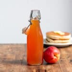 Bottle of nectarine syrup next to a nectarine.