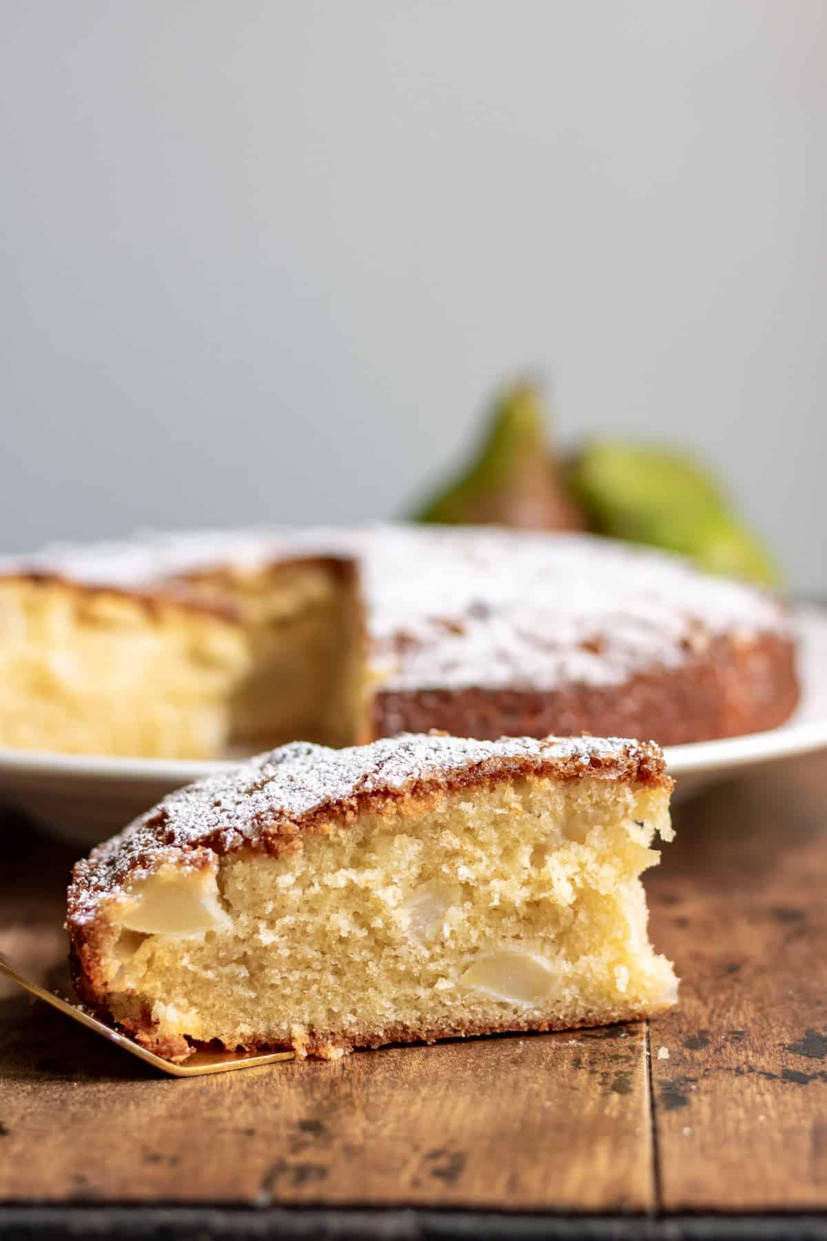 Side view of a slice of pear cake on a golden cake server.
