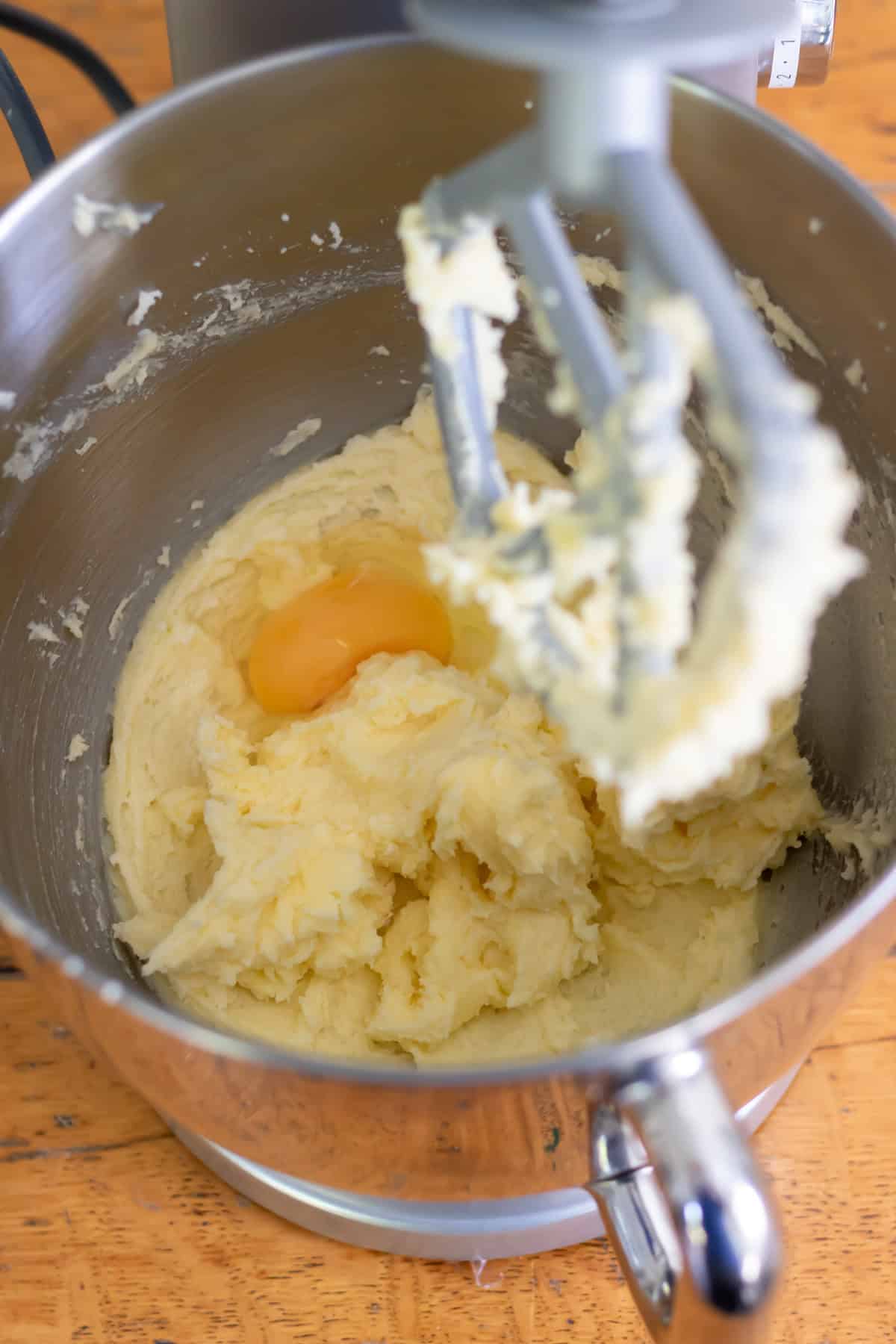 Beating the egg into the creamed butter and sugar in a stand mixer.