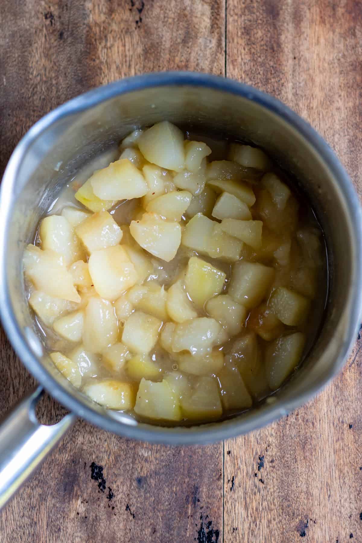 Cooked pear compote in a pot on a wooden table.