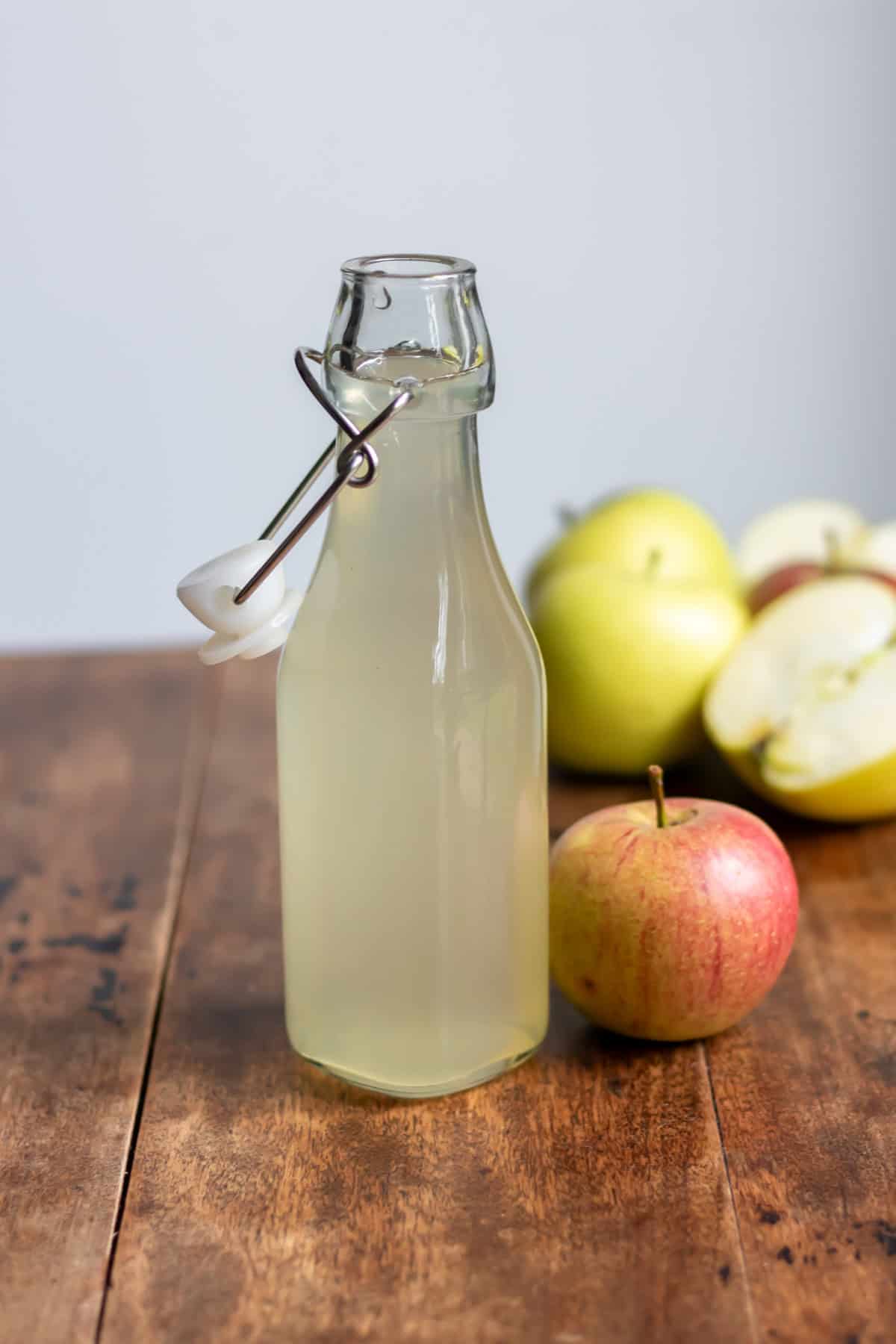 Glass bottle of apple syrup on a table.