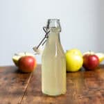 Bottle of apple syrup and apples.