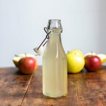 Bottle of apple syrup and apples.