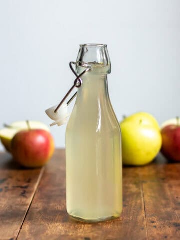 Bottle of apple syrup and apples.