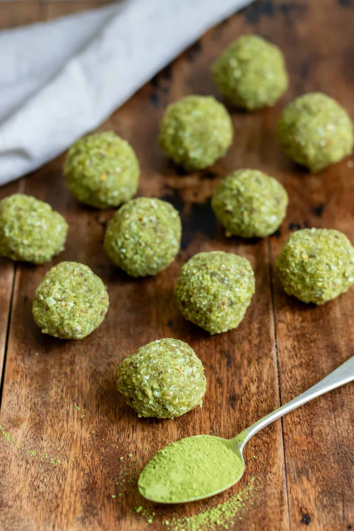 A table with matcha balls and a spoonful of matcha powder.