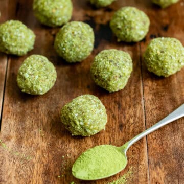 A table with matcha balls and a spoonful of matcha powder.