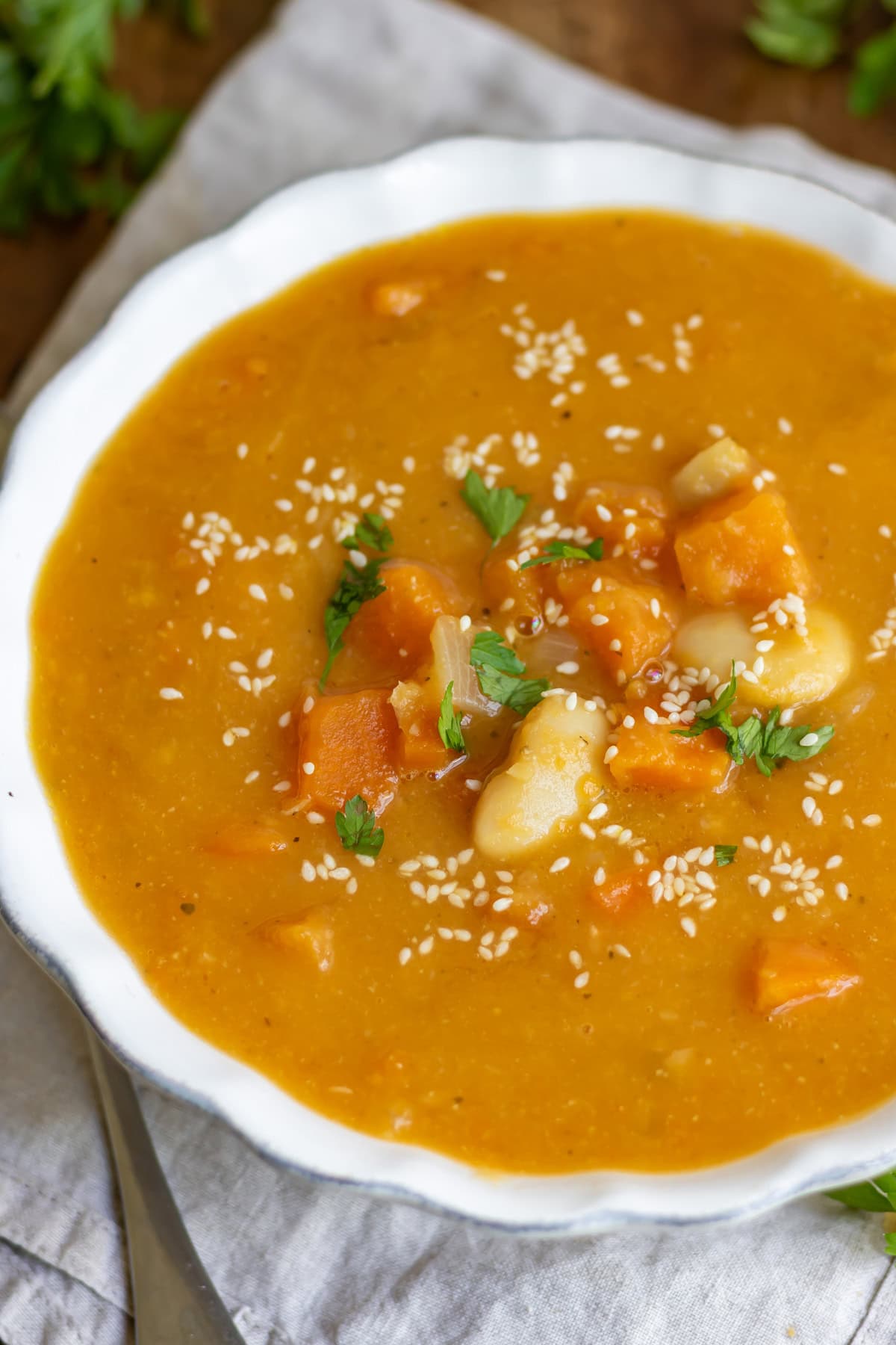 Looking down at a bowl of miso sweet potato soup that's blended with a few pieces of vegetables and beans left whole.
