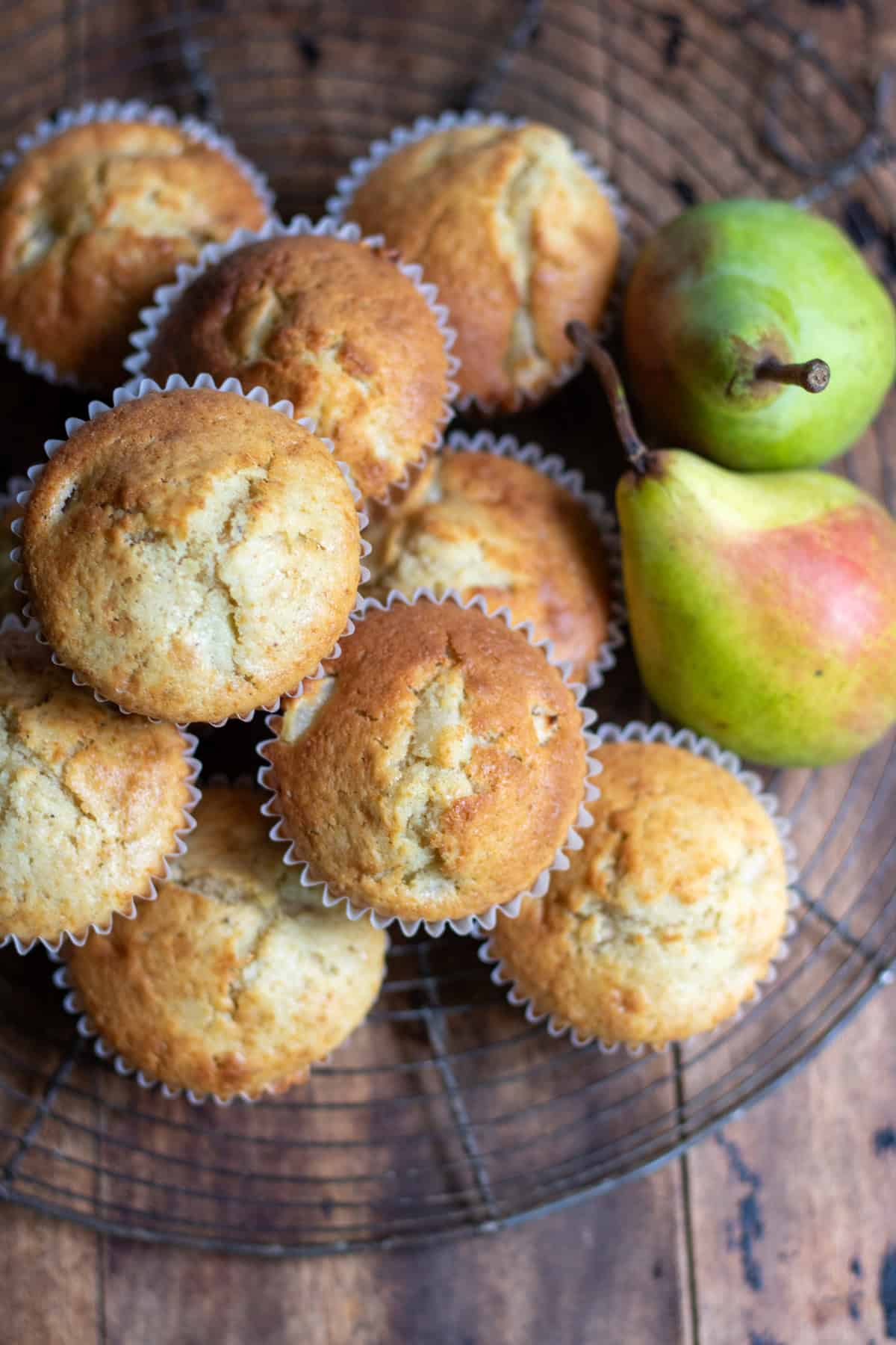 Looking down at a stack of pear muffins next to two pears.