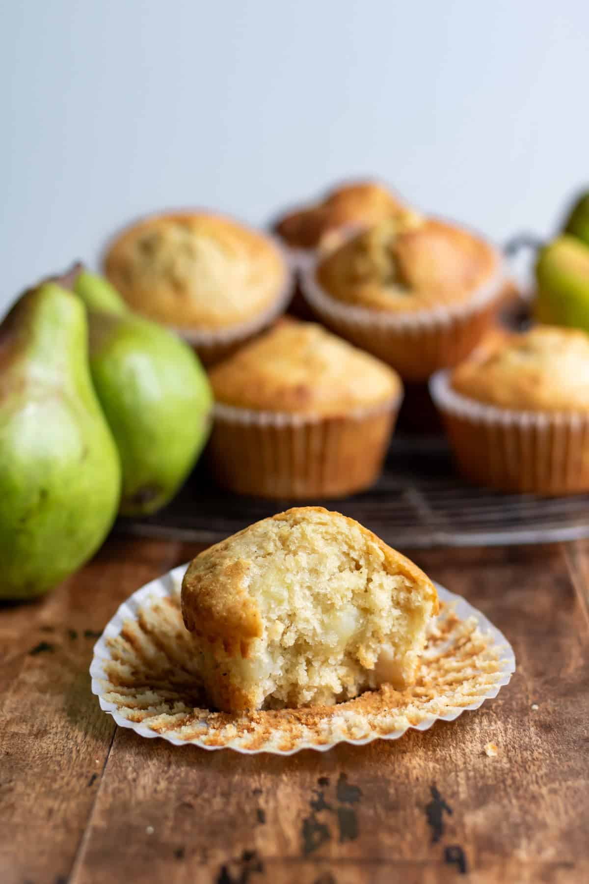 A pear muffin with a bite out, in front of more muffins.