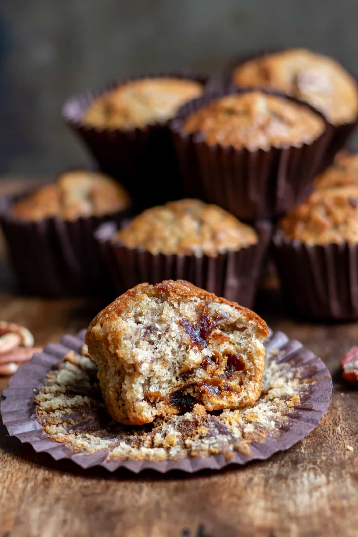 A pecan date muffin with a bite out in front of more muffins.