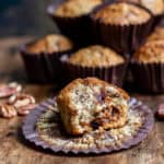 A pecan date muffin with a bite out in front of more muffins.