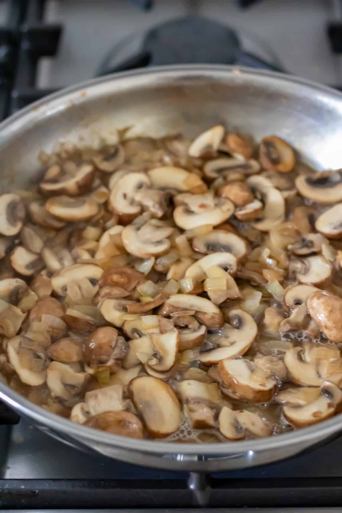 Simmering the wine with the cooked mushrooms and onions in the frying pan.