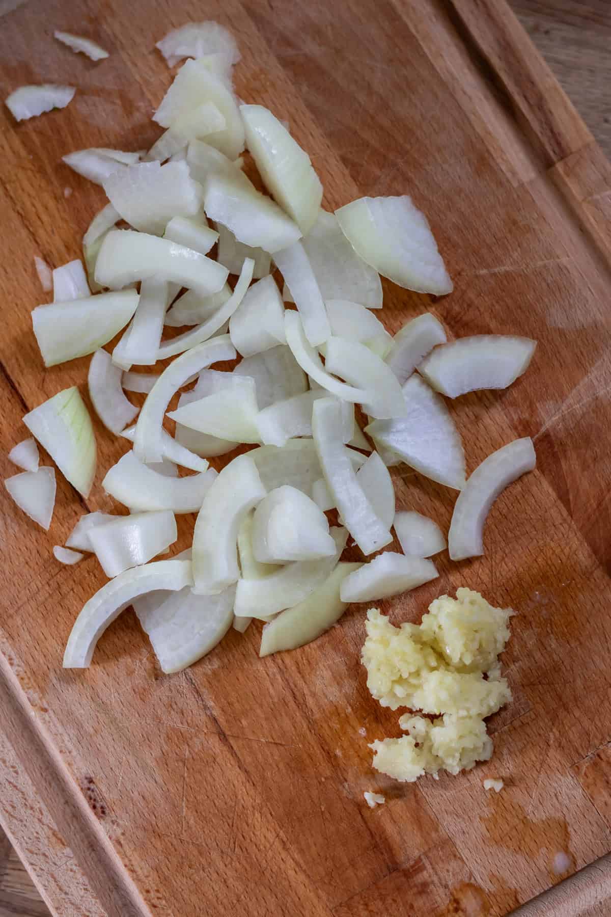 Chopped onion and minced garlic on a cutting board.