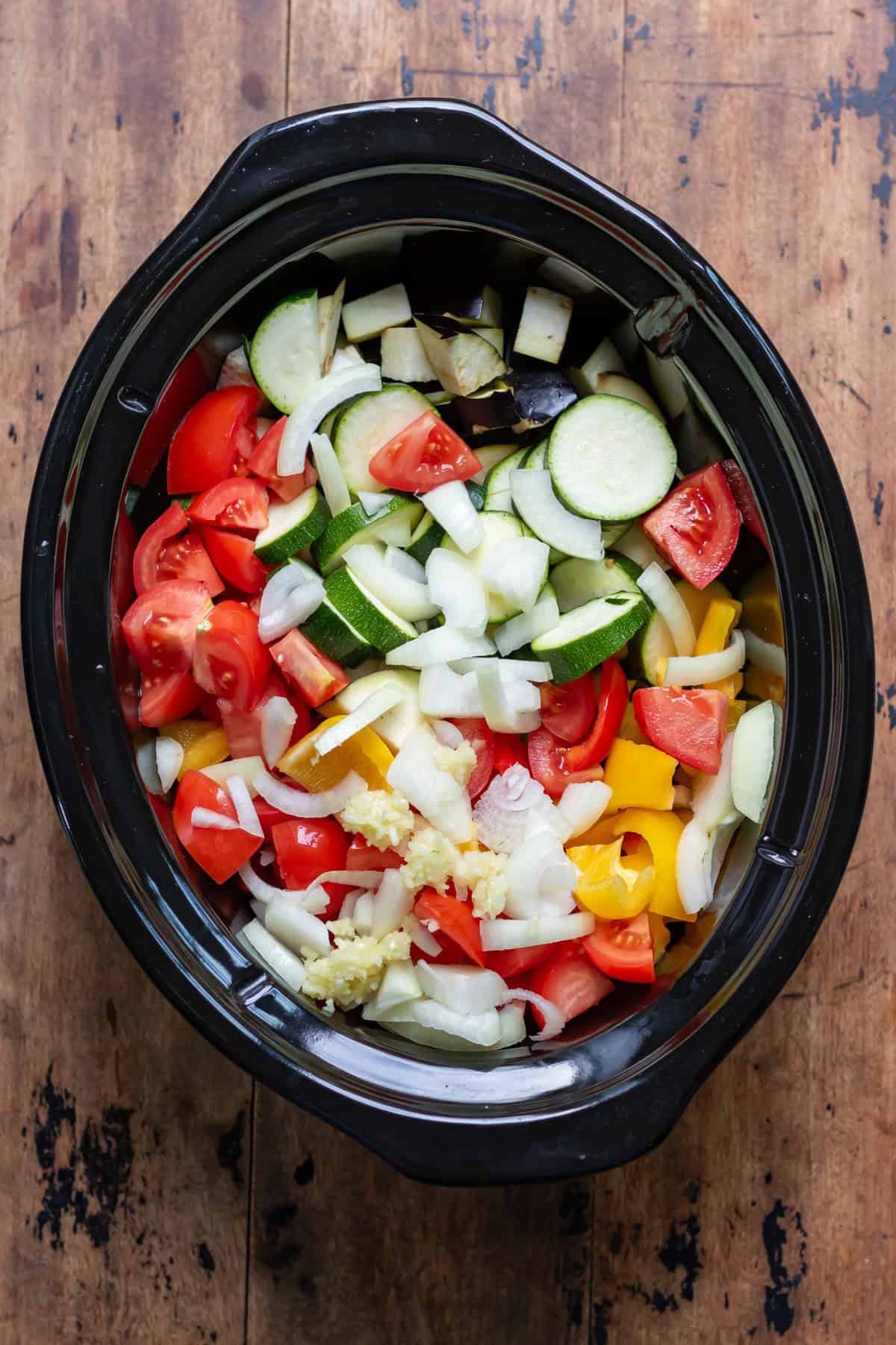 All the chopped vegetables in a slow cooker.