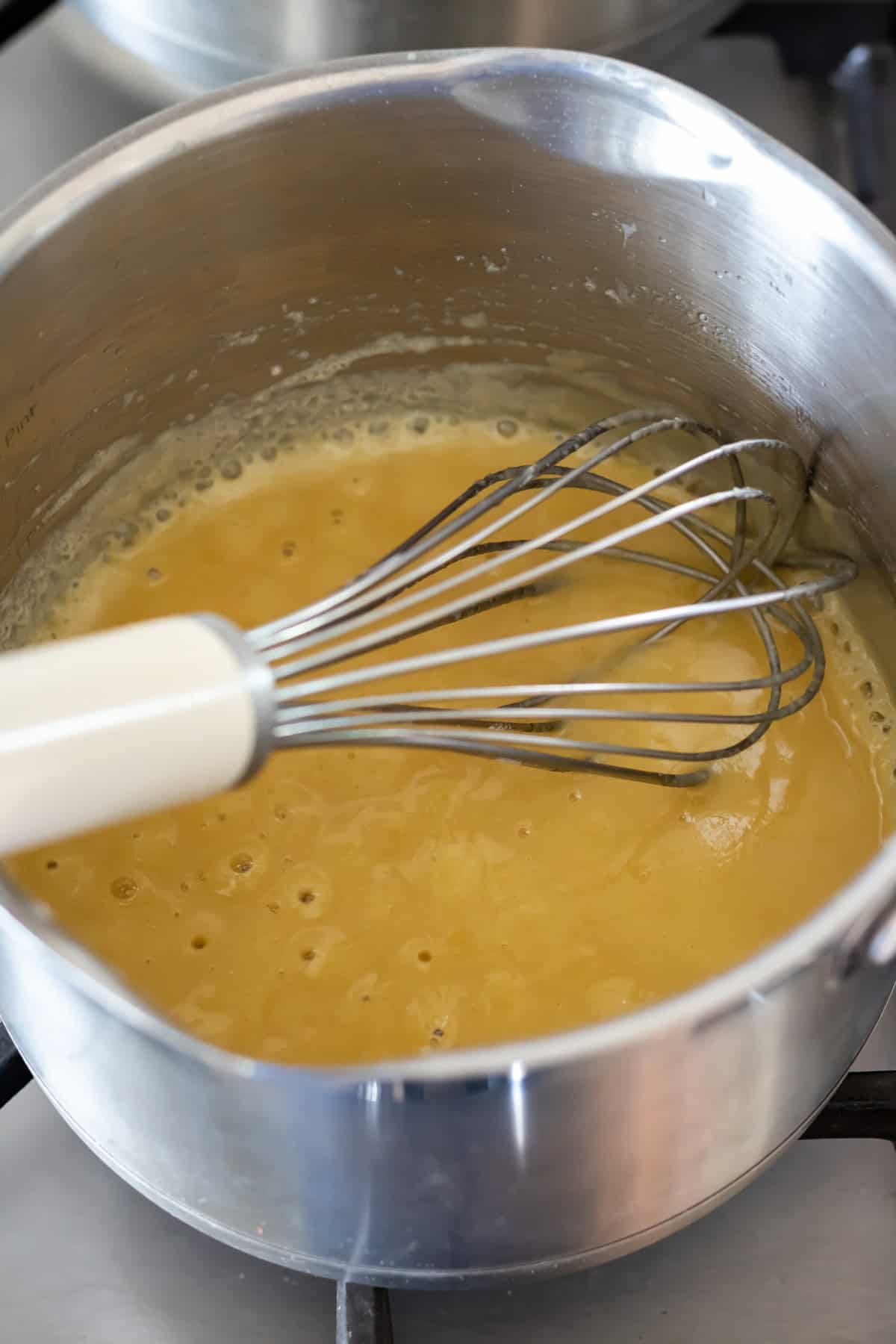 Whisking the butter and flour in a saucepan.
