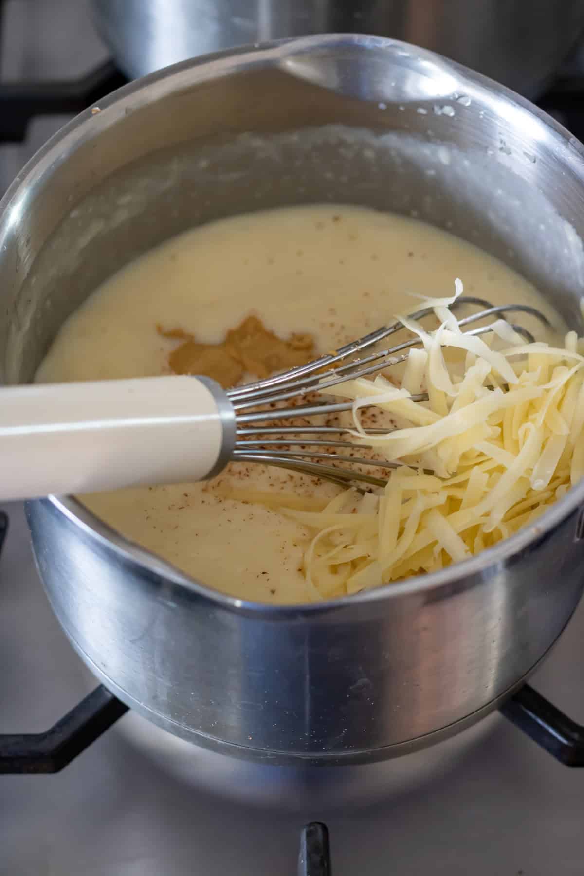 Whisking in the milk, then cheese and seasonings.