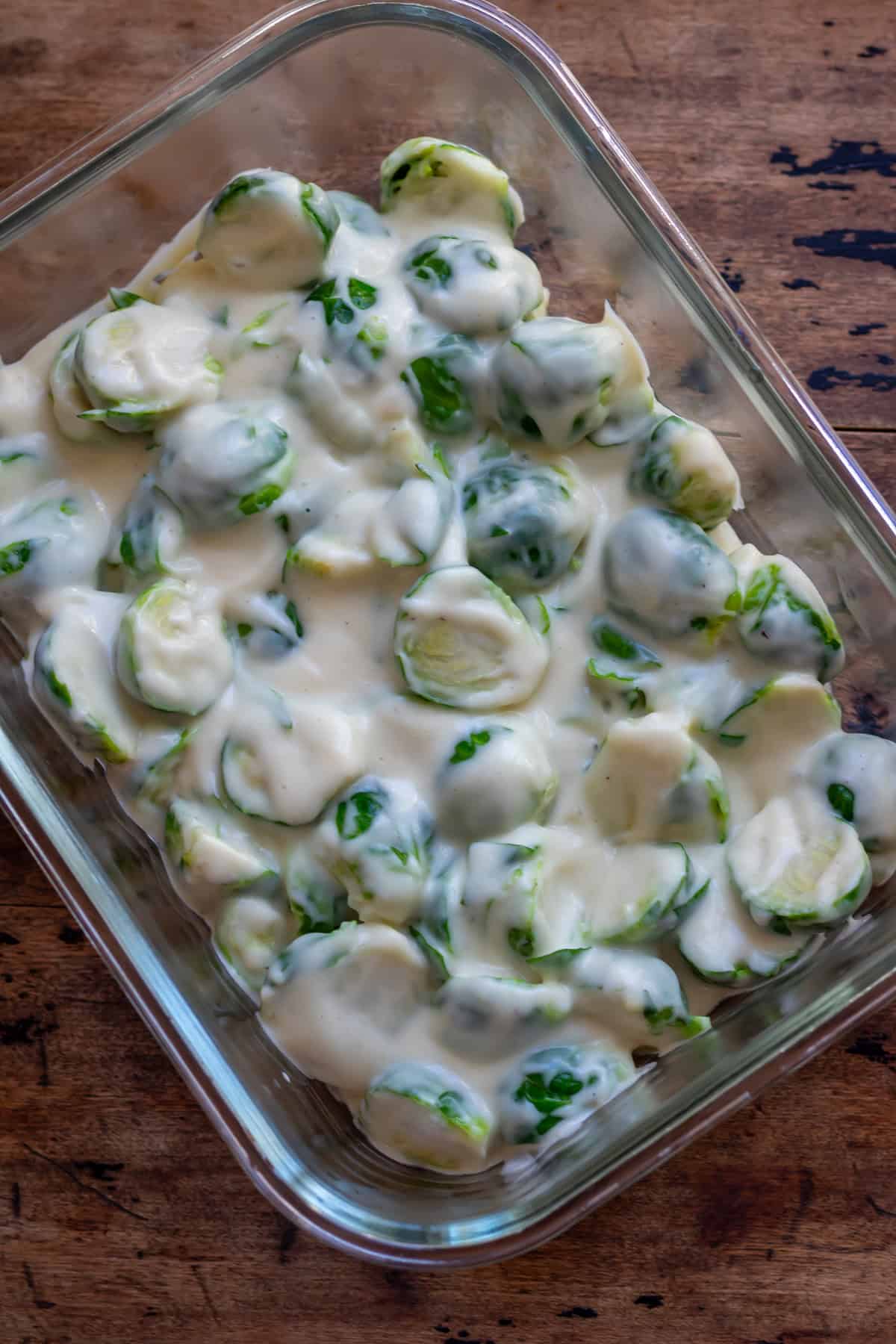 A baking dish with the brussels sprouts tossed in the cheese sauce.