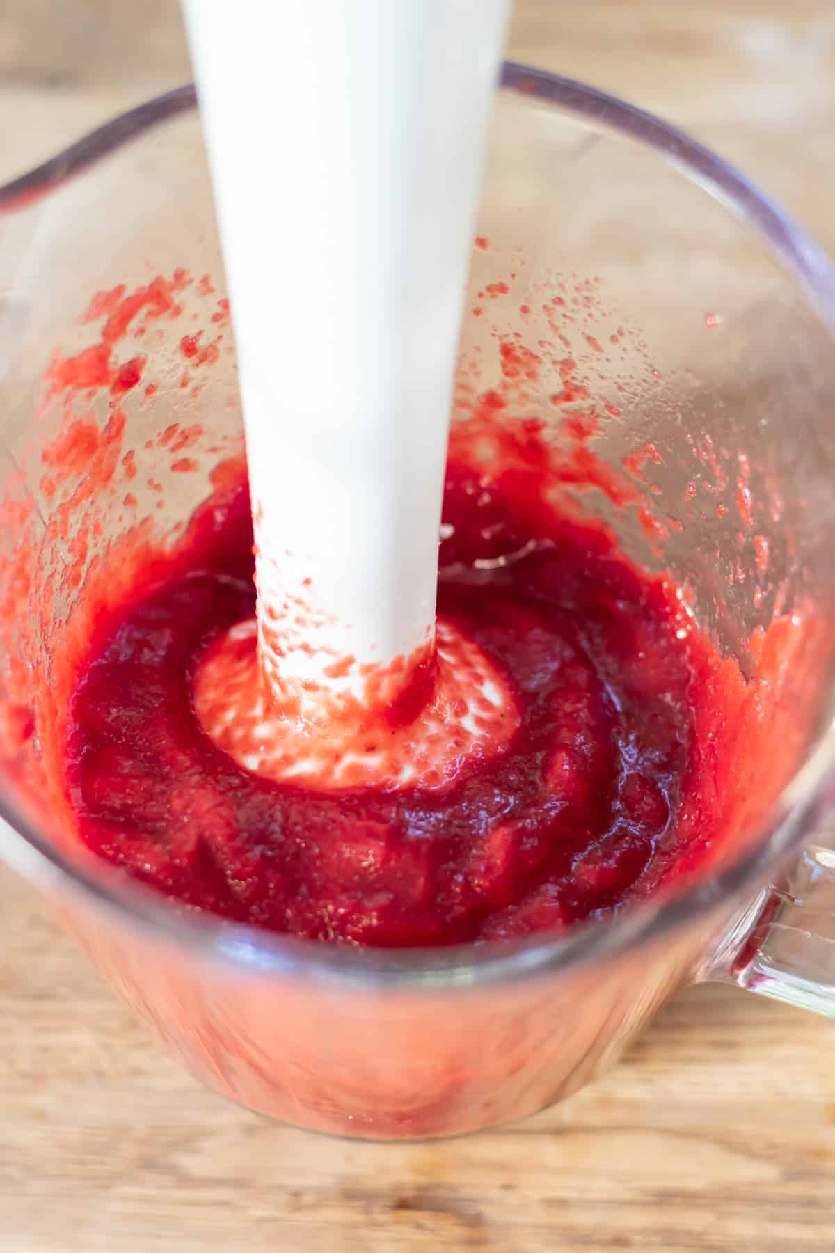 Pureeing the cooked beets with an immersion blender.