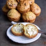 A plate with a buttered soda bread muffin in front of a pile of them.