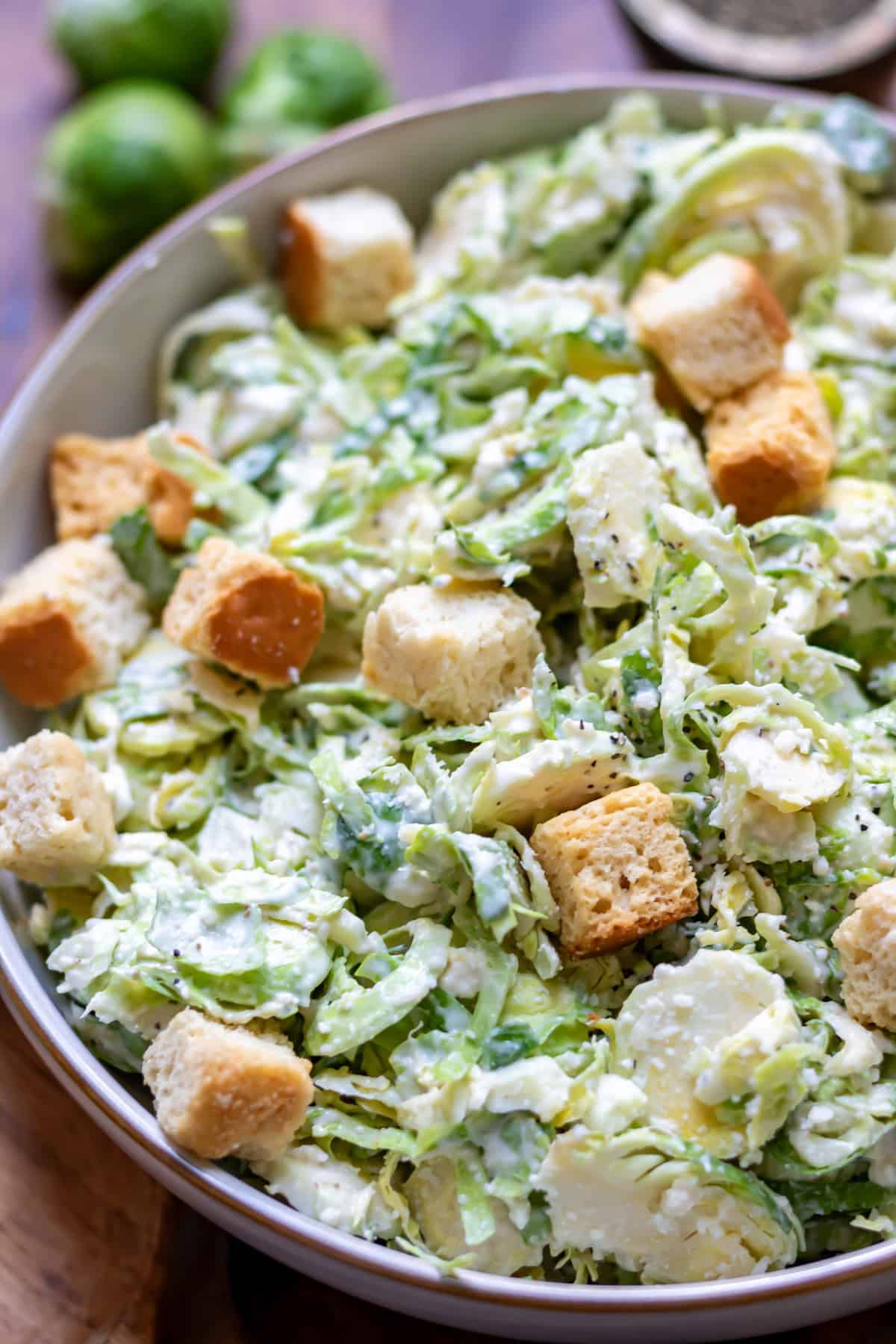 Close up of a bowl of brussels sprouts caesar slaw with croutons.